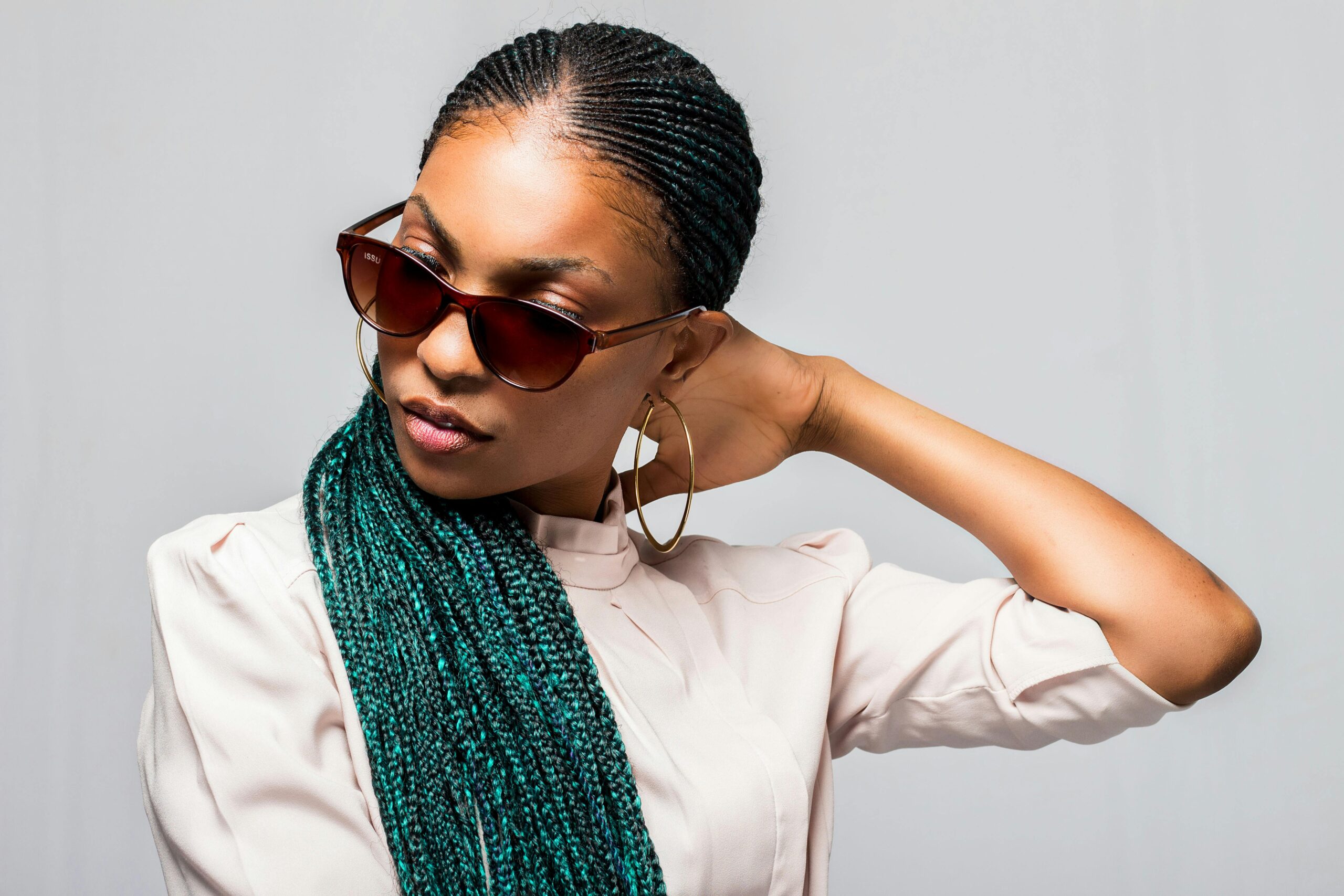 Portrait of a fashionable African woman with braids and sunglasses, exuding style.